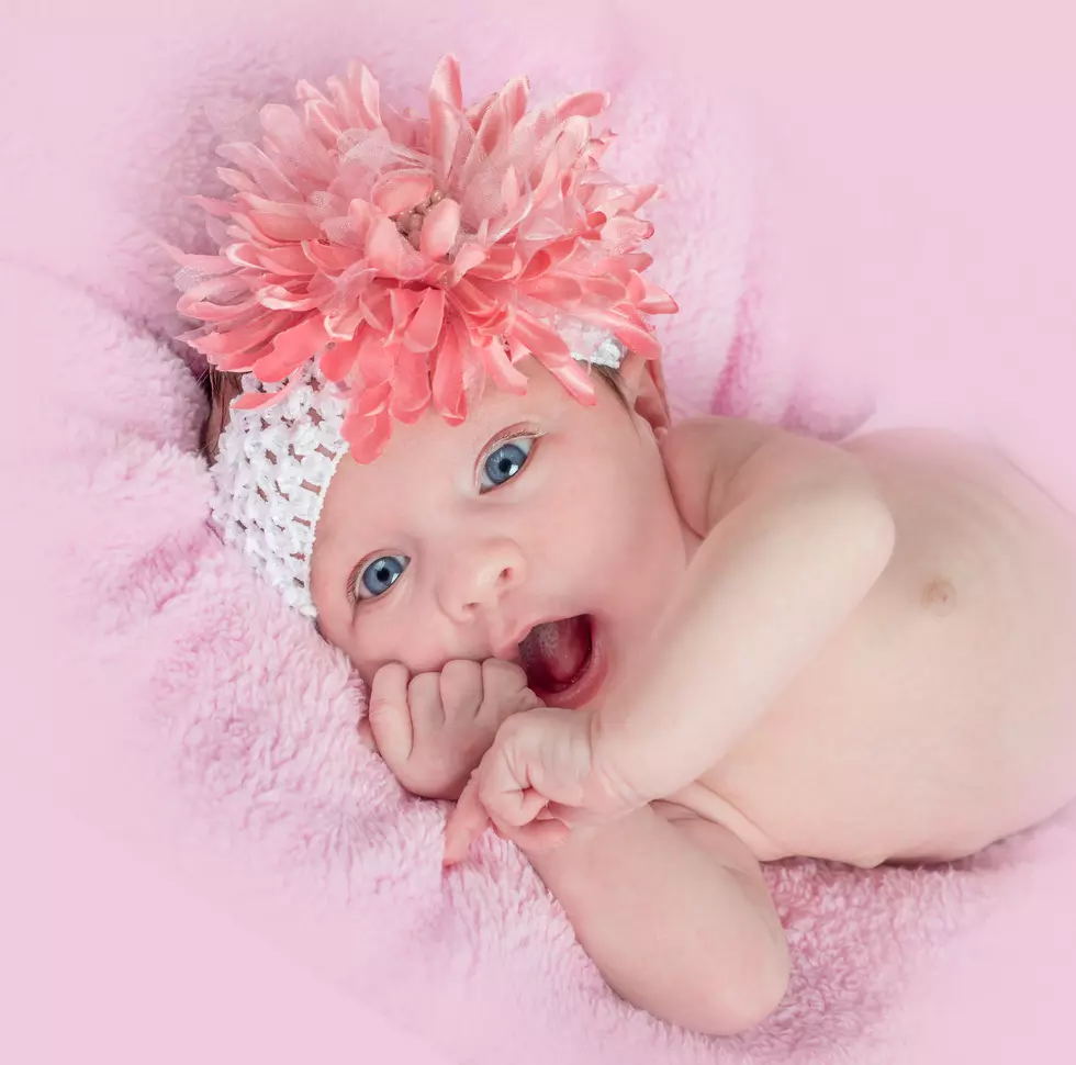 Happy blue eyed baby girl with a headband and flower